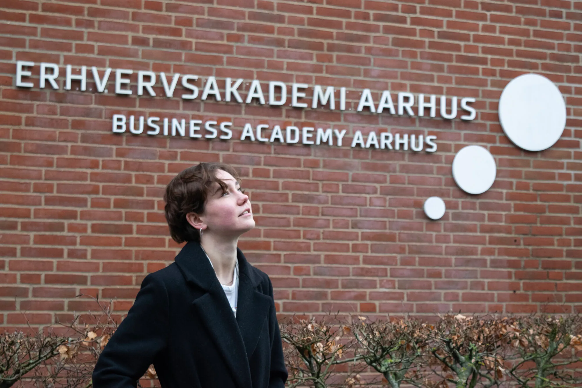 Girl standing in front of Erhvervsakademi Aarhus sign