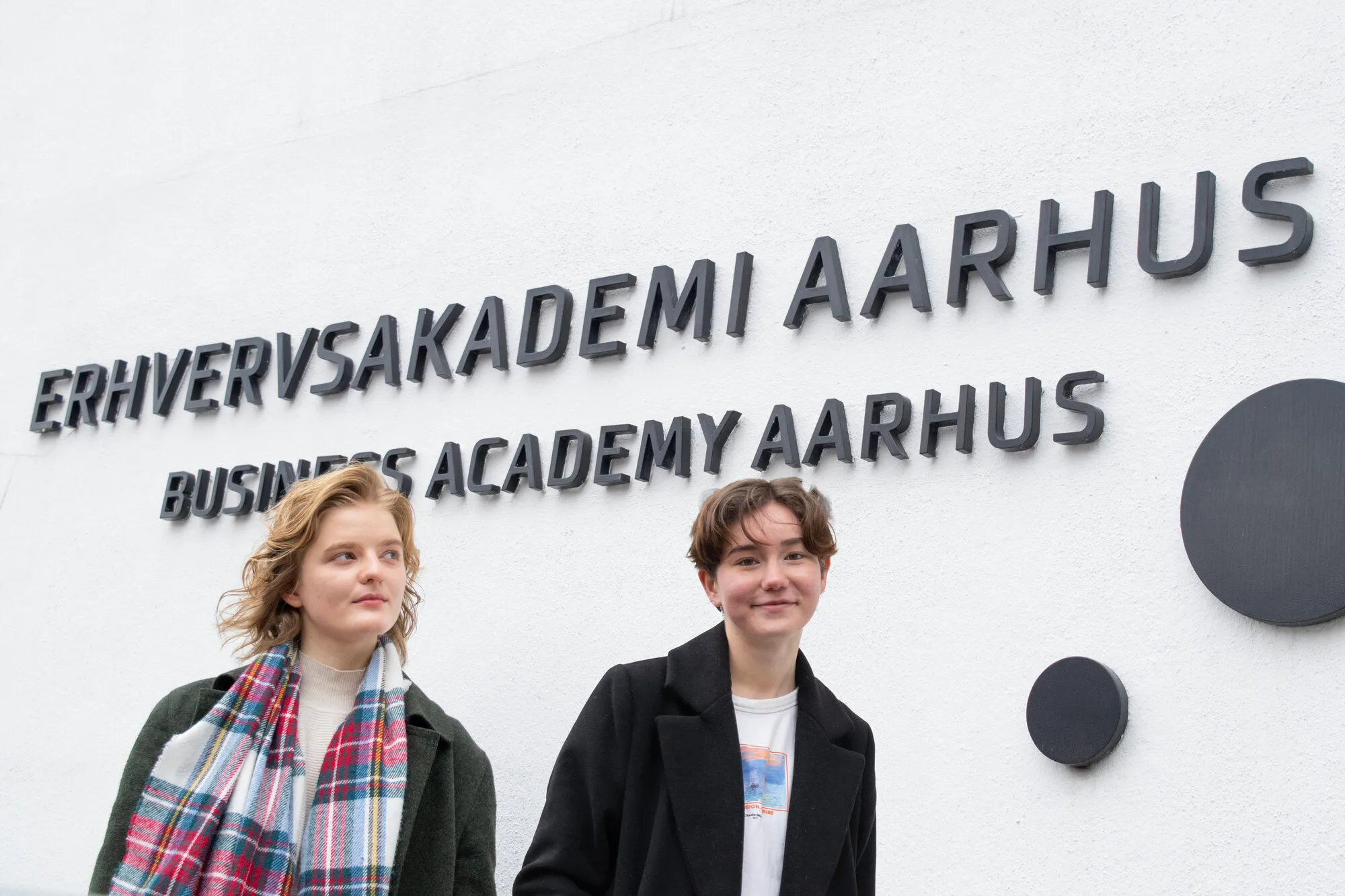 2 girls in front of school logo