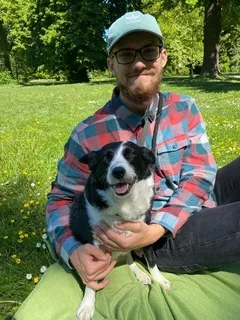 Man sitting on the blanket holding a dog.