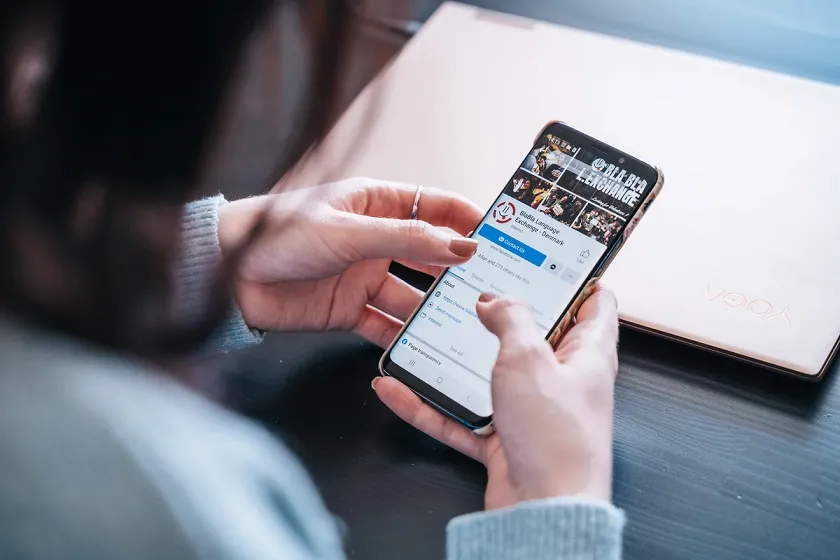 Woman holding phone with BlaBla language exchange Facebook group