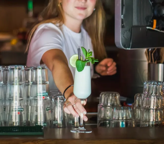 Young female student working as a bartender