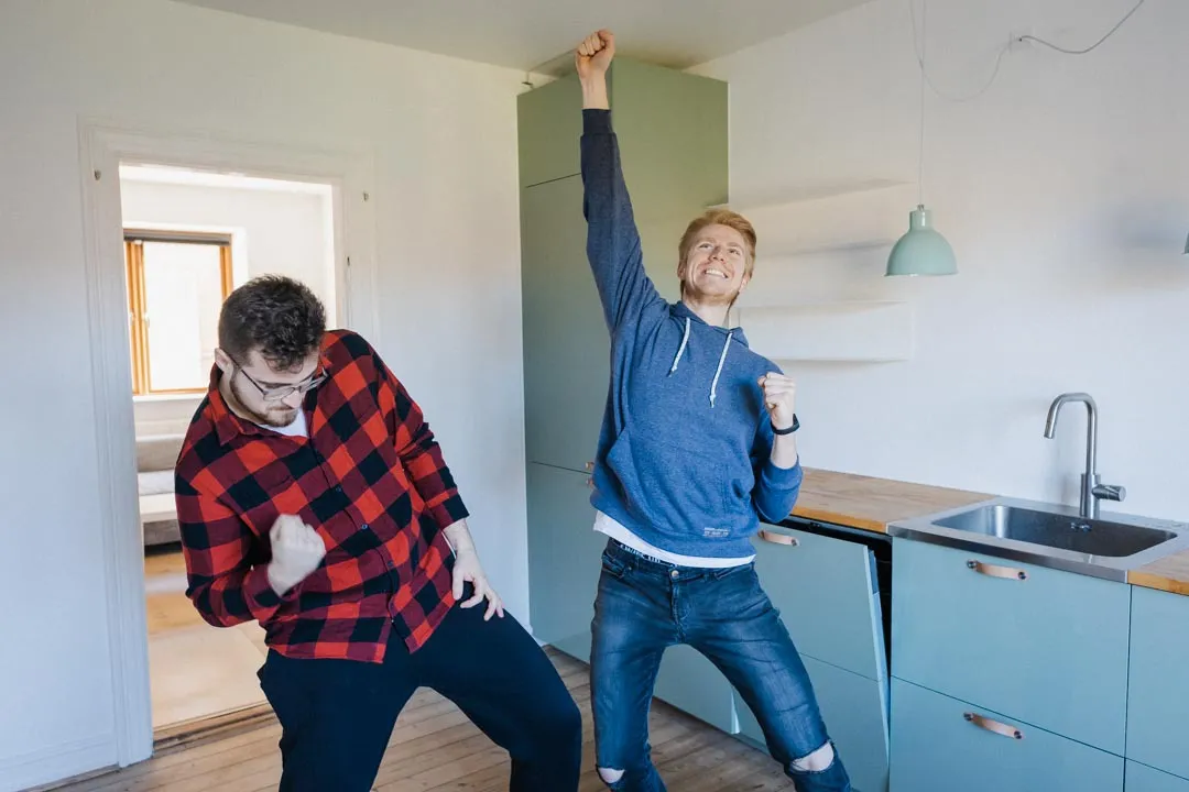 Two students in their new kitchen, looking happy.