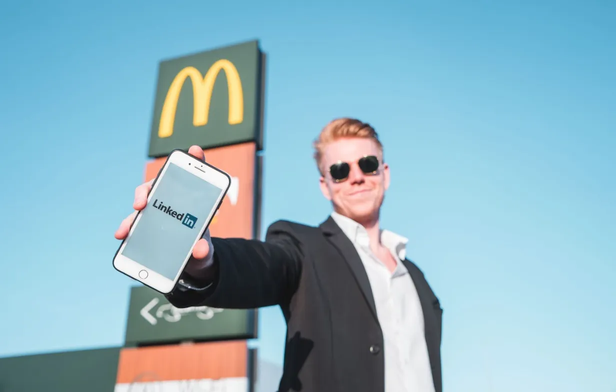 Young student holding a phone showing the LinkedIn logo